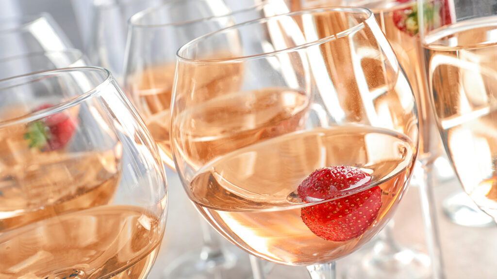 Ein Glas Roséwein mit frischer Erdbeere auf dem Tisch – Château d’Auvernier, der berühmte Œil-de-Perdrix.
