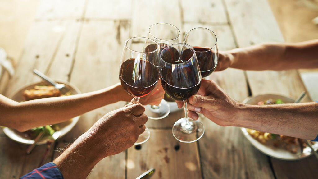 Anstossen mit Domaines Les Freres Dubois Wein über rustikalem Holztisch