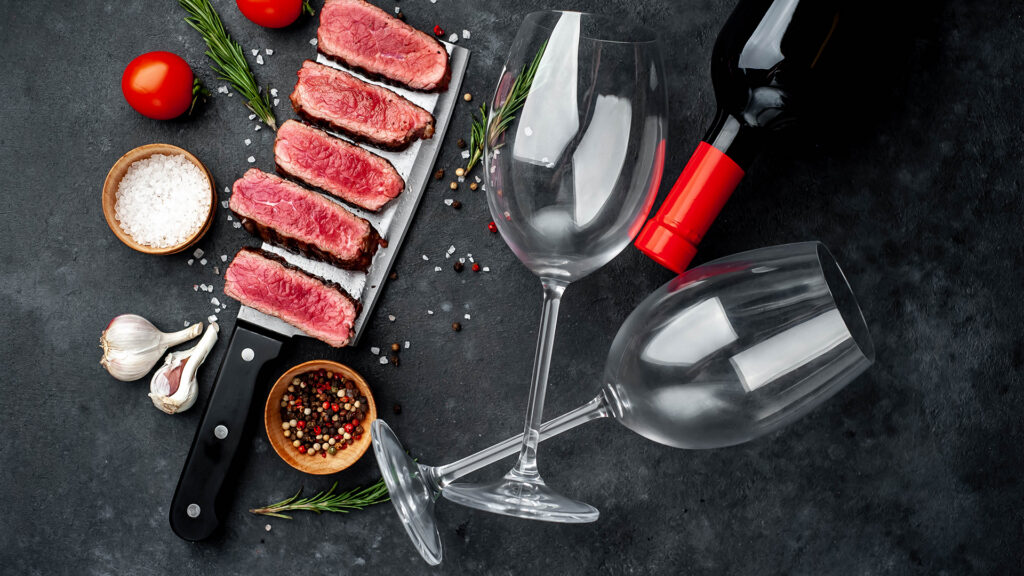 Weinregion Rioja: Rotwein neben Teller mit Fleischgericht auf Tisch