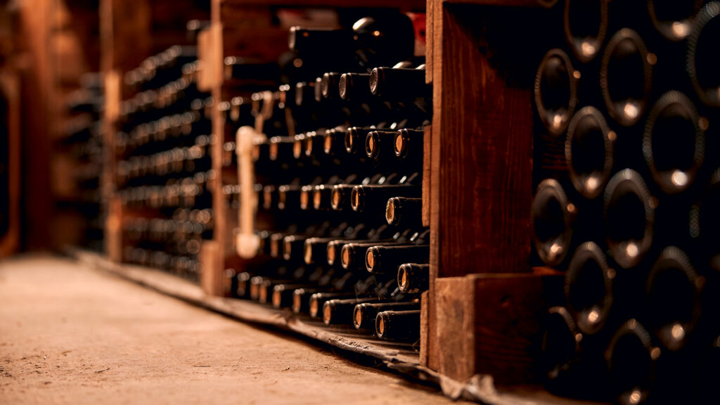 Regal mit mehreren Reihen liegender Weinflaschen in einem Weinkeller.