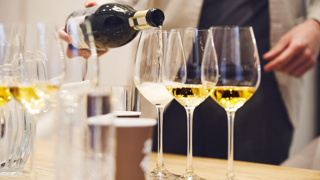 ein Mann schenkt Weisswein in ein Glas ein für eine Degustation